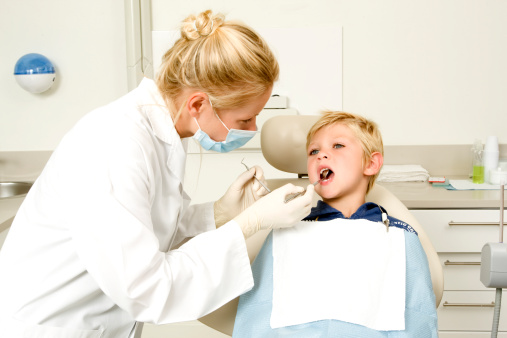 Female dentist examining little boy